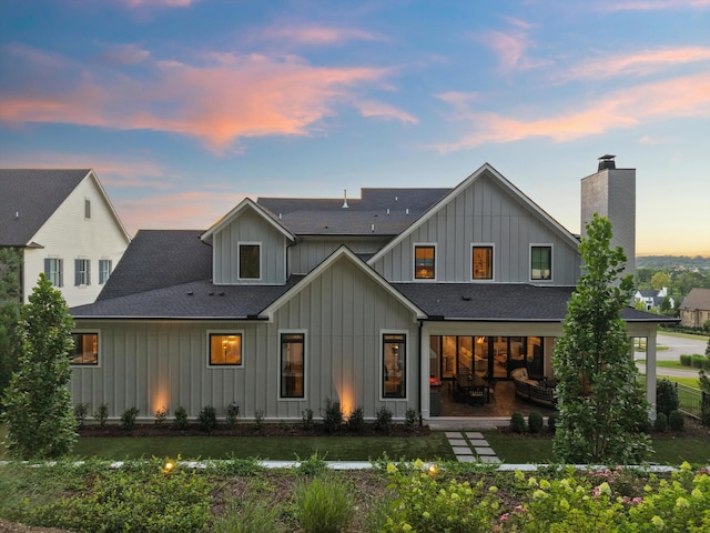 8227 Heirloom Blvd, College Grove, TN 37046 - rear view of house with board and batten siding, a shingled roof, a chimney, a patio area, and a lawn