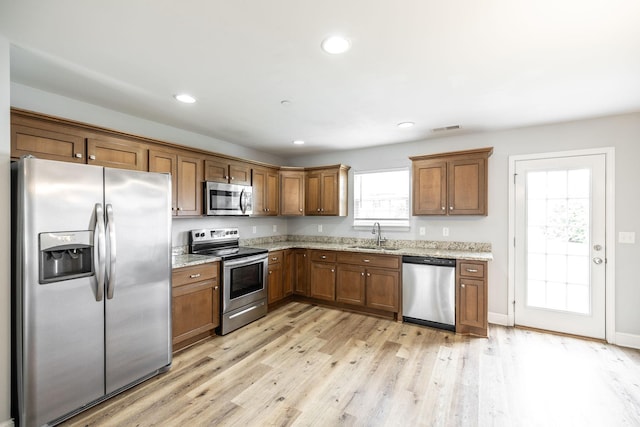 2075 Downstream Dr, Ashland City, TN 37015 - kitchen with appliances with stainless steel finishes, light wood-style flooring, brown cabinetry, light stone countertops, and recessed lighting