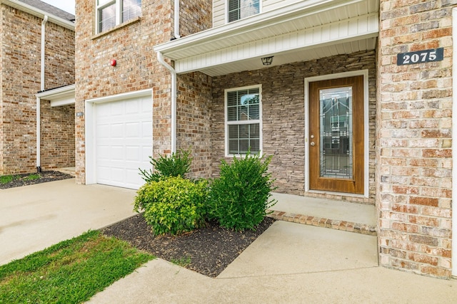 2075 Downstream Dr, Ashland City, TN 37015 - doorway to property with an attached garage, concrete driveway, brick siding, and covered porch