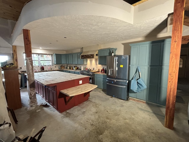 201 Summit Dr, Linden, TN 37096 - kitchen featuring appliances with stainless steel finishes, wall chimney exhaust hood, a kitchen island, unfinished concrete flooring, and a textured ceiling