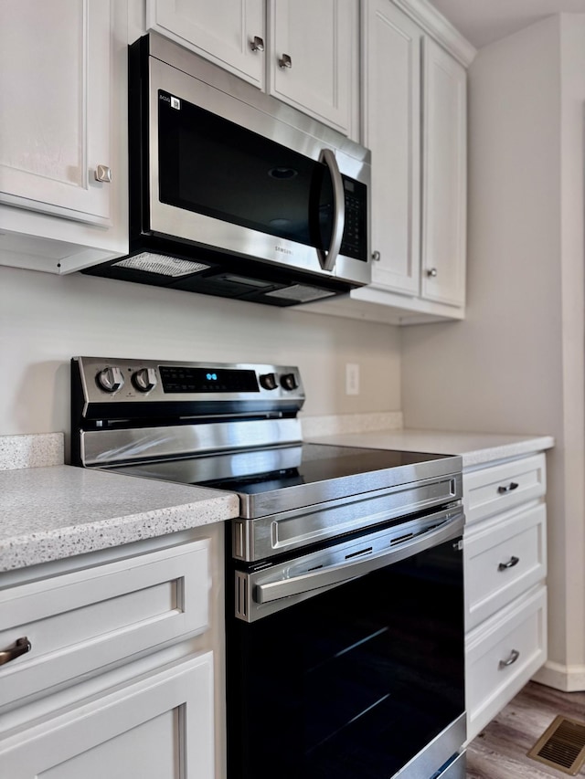 1122 Brannon Rd, Lawrenceburg, TN 38464 - kitchen featuring appliances with stainless steel finishes, wood finished floors, and white cabinets
