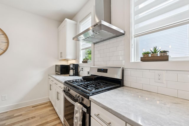 1111 Baptist World Center Dr Unit 5, Nashville, TN 37207 - kitchen with stainless steel gas stove, wall chimney range hood, decorative backsplash, light stone counters, and white cabinets