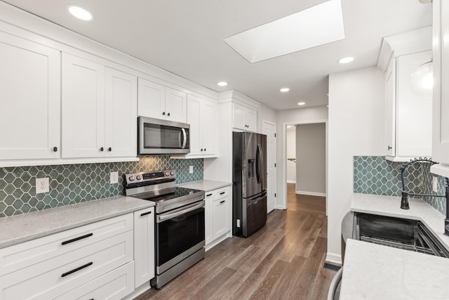 8205 Brownstone Ext, Cross Plains, TN 37049 - kitchen with appliances with stainless steel finishes, white cabinets, tasteful backsplash, a skylight, and recessed lighting