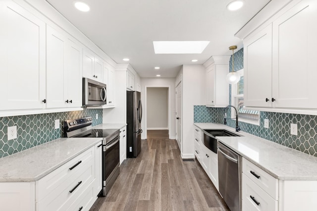 8205 Brownstone Ext, Cross Plains, TN 37049 - kitchen featuring appliances with stainless steel finishes, a skylight, tasteful backsplash, wood finished floors, and white cabinetry