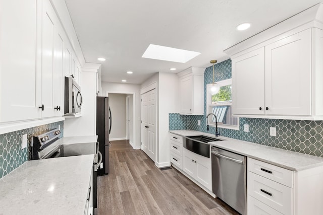 8205 Brownstone Ext, Cross Plains, TN 37049 - kitchen featuring stainless steel appliances, a skylight, decorative backsplash, white cabinets, and recessed lighting