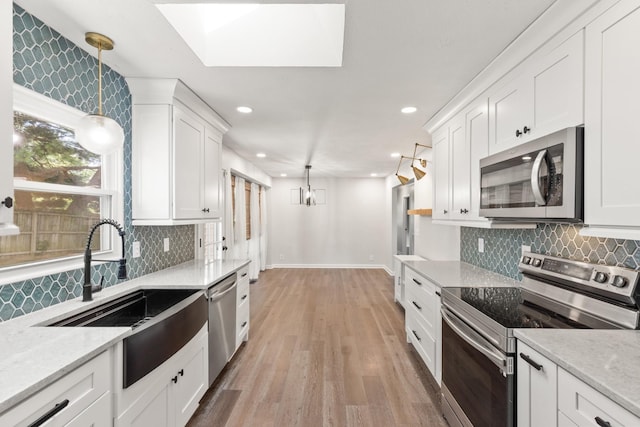 8205 Brownstone Ext, Cross Plains, TN 37049 - kitchen with stainless steel appliances, white cabinetry, light wood finished floors, decorative light fixtures, and recessed lighting