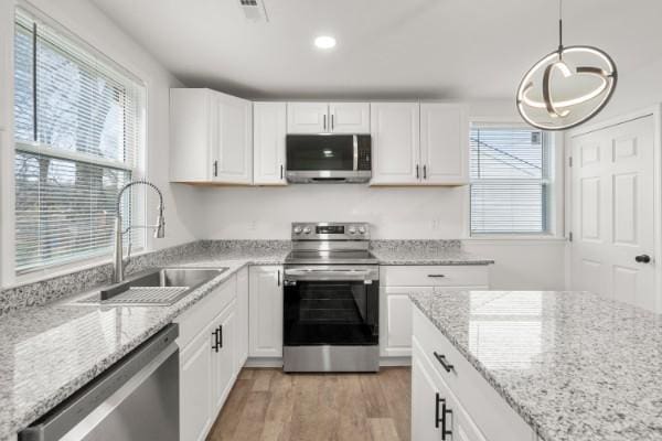 3211 Mayer Ln, Nashville, TN 37218 - kitchen featuring stainless steel appliances, white cabinets, light wood-style flooring, recessed lighting, and light stone countertops