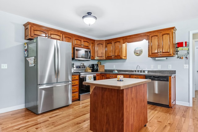 216 Desperado Ave, Pulaski, TN 38478 - kitchen featuring appliances with stainless steel finishes, light wood finished floors, brown cabinetry, a kitchen island, and dark countertops