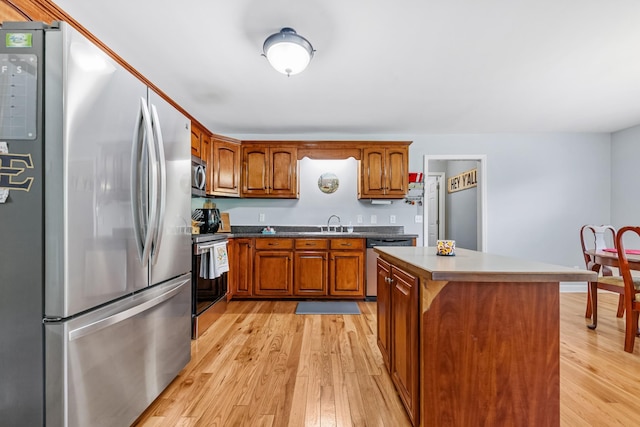 216 Desperado Ave, Pulaski, TN 38478 - kitchen with stainless steel appliances, light wood-type flooring, brown cabinetry, and a kitchen island