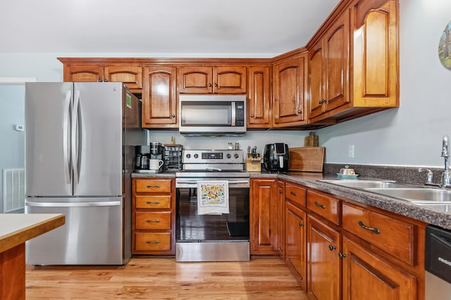 216 Desperado Ave, Pulaski, TN 38478 - kitchen with appliances with stainless steel finishes, brown cabinets, light wood-type flooring, and dark countertops