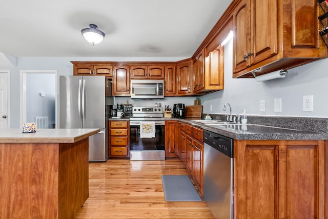 216 Desperado Ave, Pulaski, TN 38478 - kitchen with stainless steel appliances, brown cabinetry, light wood-style flooring, and dark countertops