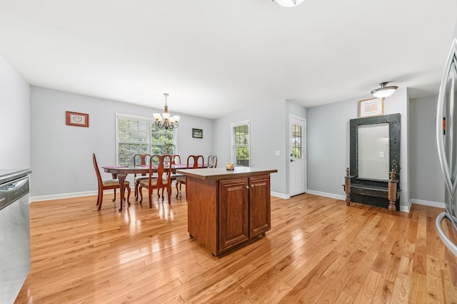 216 Desperado Ave, Pulaski, TN 38478 - kitchen with stainless steel dishwasher, light wood finished floors, a chandelier, a kitchen island, and brown cabinetry