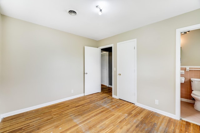 201 Sterry Ct, Antioch, TN 37013 - unfurnished bedroom with light wood finished floors, tile walls, and connected bathroom