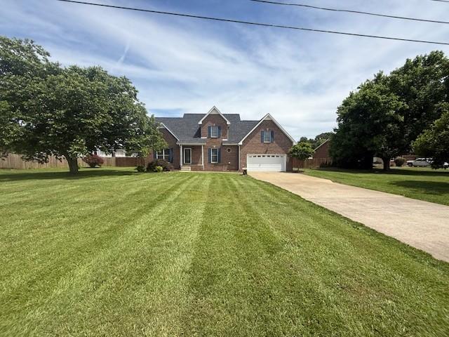 2750 Shepherds Ct, Woodlawn, TN 37191 - view of front of house with concrete driveway, a front yard, an attached garage, and brick siding