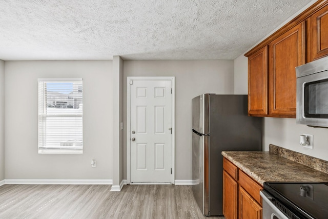 5428 Cedar Ash Xing, Antioch, TN 37013 - kitchen featuring light wood-style floors, stainless steel appliances, brown cabinetry, dark countertops, and a textured ceiling