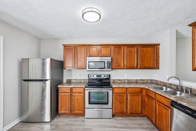 5428 Cedar Ash Xing, Antioch, TN 37013 - kitchen with appliances with stainless steel finishes, a textured ceiling, light wood-type flooring, and brown cabinetry