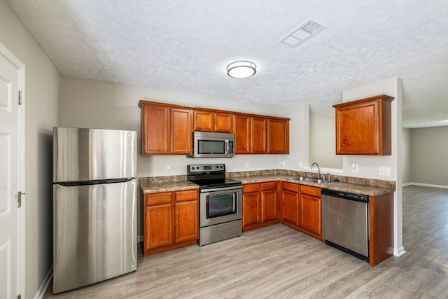5428 Cedar Ash Xing, Antioch, TN 37013 - kitchen with stainless steel appliances, light wood-style floors, brown cabinets, a textured ceiling, and dark countertops