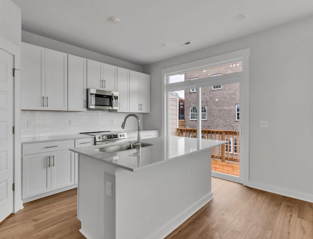510 Hinton St, Lebanon, TN 37090 - kitchen featuring stainless steel appliances, light wood-style flooring, backsplash, a kitchen island with sink, and white cabinets