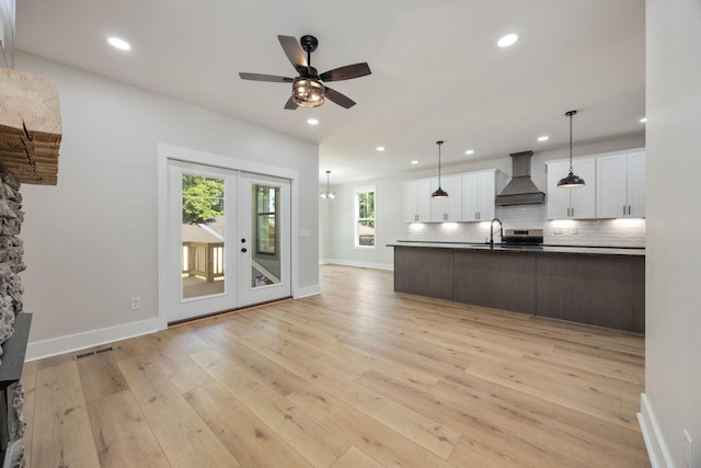 403 Boren St, Springfield, TN 37172 - kitchen with wall chimney exhaust hood, dark countertops, backsplash, light wood-type flooring, and white cabinetry