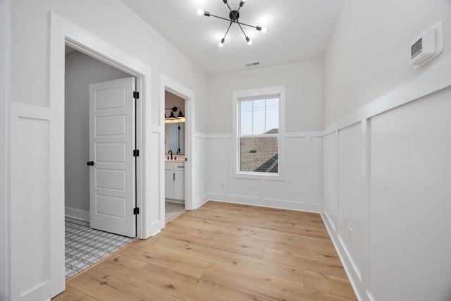 403 Boren St, Springfield, TN 37172 - spare room featuring a chandelier, light wood-style flooring, wainscoting, and a decorative wall
