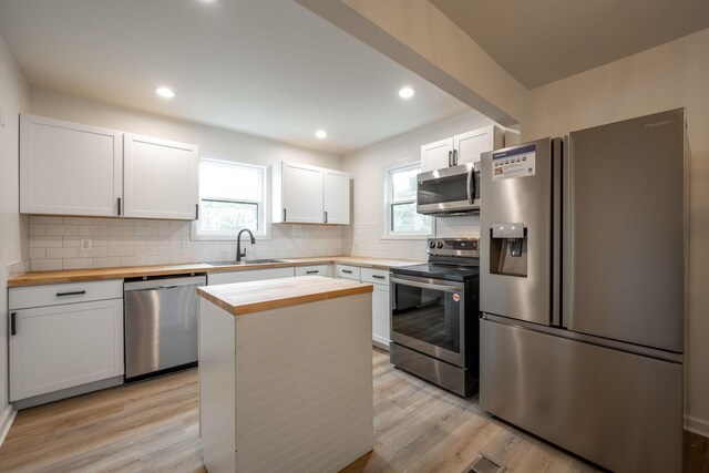 35 Agnes Ave, Chattanooga, TN 37406 - kitchen with appliances with stainless steel finishes, butcher block countertops, light wood-type flooring, decorative backsplash, and recessed lighting