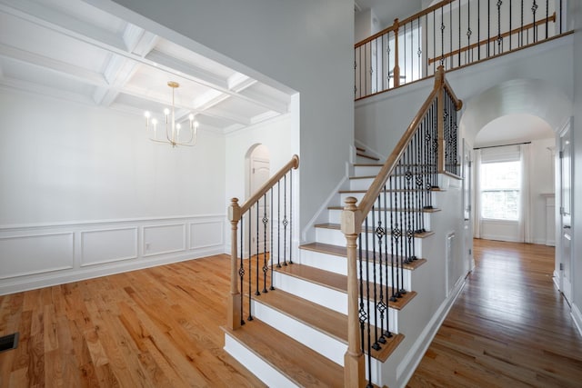 8539 Lexie Ln, Ooltewah, TN 37363 - stairway featuring arched walkways, wood finished floors, a chandelier, beam ceiling, and coffered ceiling