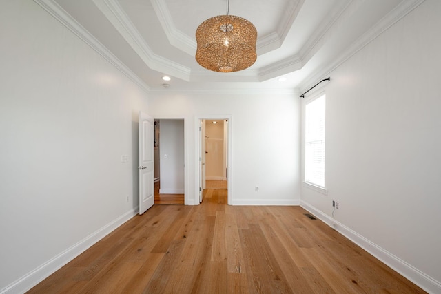 8539 Lexie Ln, Ooltewah, TN 37363 - empty room with a tray ceiling, ornamental molding, light wood-style flooring, recessed lighting, and a chandelier
