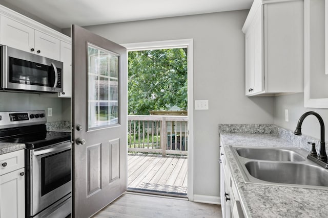 521 5th Ave N, Lewisburg, TN 37091 - kitchen featuring appliances with stainless steel finishes, white cabinets, light countertops, and light wood-style flooring