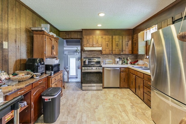 2802 Canterbury Dr, Springfield, TN 37172 - kitchen featuring stainless steel appliances, wood walls, a textured ceiling, tasteful backsplash, and brown cabinetry