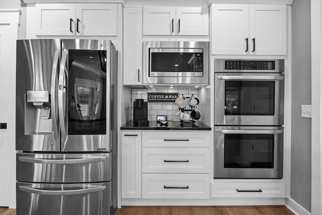 1014 Douglas Ct, Dickson, TN 37055 - kitchen featuring stainless steel appliances, dark countertops, tasteful backsplash, white cabinetry, and wood finished floors