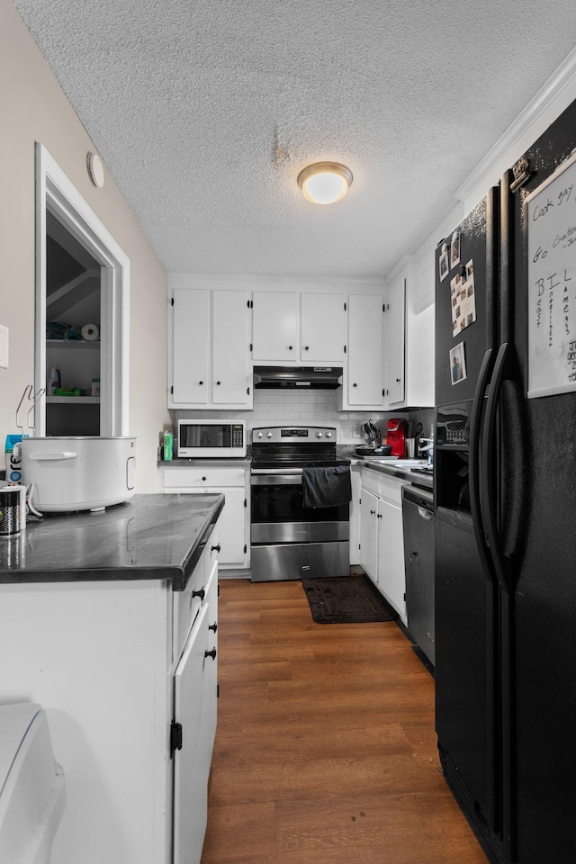 309 Shawnee Dr, Columbia, TN 38401 - kitchen with stainless steel appliances, under cabinet range hood, a textured ceiling, dark countertops, and white cabinetry
