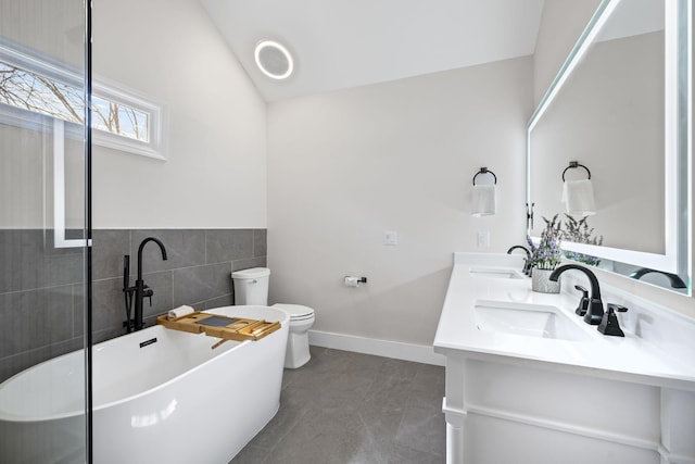 405 Wexford Ct, Franklin, TN 37069 - bathroom with tile walls, a freestanding tub, double vanity, vaulted ceiling, and tile patterned floors
