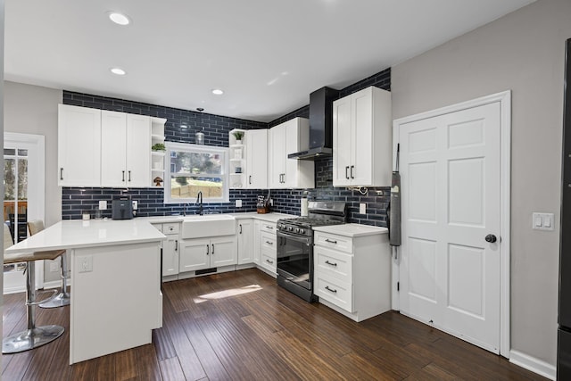 405 Wexford Ct, Franklin, TN 37069 - kitchen with stainless steel gas range oven, wall chimney range hood, open shelves, a peninsula, and dark wood-style flooring