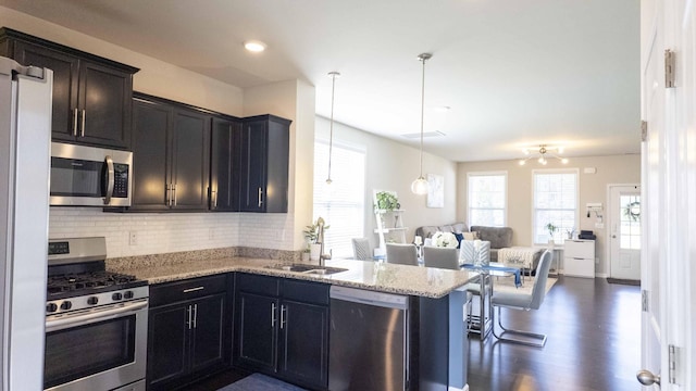 4289 Grapevine Loop, Smyrna, TN 37167 - kitchen featuring stainless steel appliances, open floor plan, tasteful backsplash, light stone countertops, and hanging light fixtures