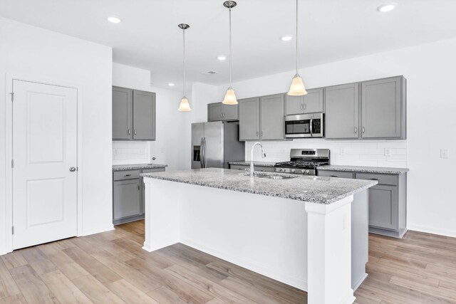 1234 English Oak Dr, Clarksville, TN 37043 - kitchen featuring appliances with stainless steel finishes, gray cabinetry, backsplash, light wood finished floors, and light stone counters