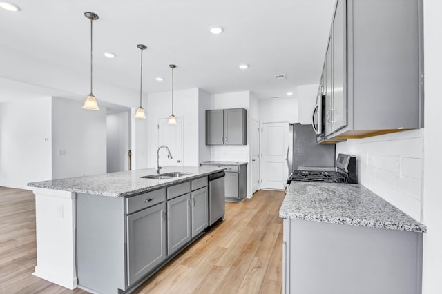 1234 English Oak Dr, Clarksville, TN 37043 - kitchen featuring gray cabinetry, stainless steel appliances, decorative backsplash, a center island with sink, and light wood-style flooring