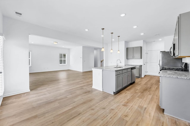 1234 English Oak Dr, Clarksville, TN 37043 - kitchen with gray cabinetry, stainless steel appliances, open floor plan, light wood-style floors, and an island with sink