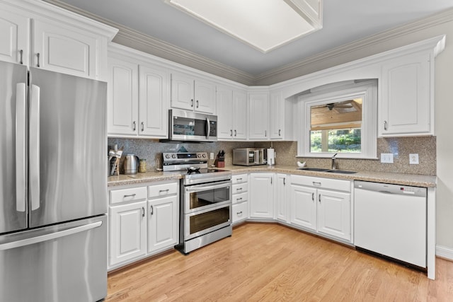 162 N Berwick Ln, Franklin, TN 37069 - kitchen with stainless steel appliances, white cabinetry, light countertops, light wood-style floors, and crown molding