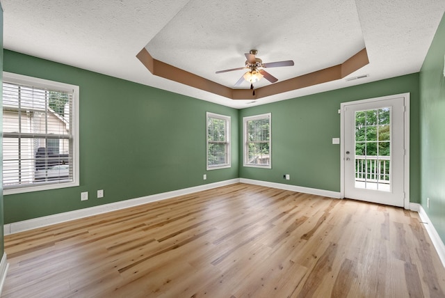 3158 Whitetail Dr, Clarksville, TN 37043 - empty room featuring a textured ceiling, ceiling fan, light wood-type flooring, plenty of natural light, and a raised ceiling