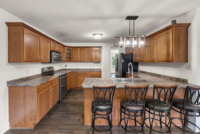 3158 Whitetail Dr, Clarksville, TN 37043 - kitchen featuring stainless steel appliances, a peninsula, dark wood-style floors, brown cabinets, and a breakfast bar area