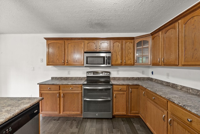 3158 Whitetail Dr, Clarksville, TN 37043 - kitchen featuring stainless steel appliances, dark wood-type flooring, dark countertops, brown cabinets, and a textured ceiling