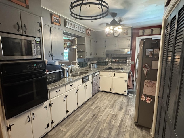 123 Coffman Dr, Fort Oglethorpe, GA 30742 - kitchen with stainless steel appliances, light wood-type flooring, under cabinet range hood, a chandelier, and light stone countertops