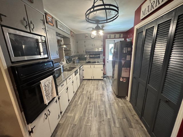 123 Coffman Dr, Fort Oglethorpe, GA 30742 - kitchen featuring appliances with stainless steel finishes, light wood-style floors, a chandelier, white cabinets, and under cabinet range hood