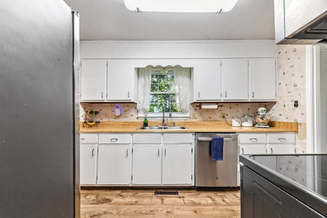 1150 Mattox Town Rd, Lawrenceburg, TN 38464 - kitchen with stainless steel appliances, light wood-type flooring, light countertops, white cabinetry, and a textured ceiling