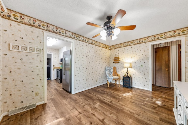 1150 Mattox Town Rd, Lawrenceburg, TN 38464 - unfurnished room featuring ceiling fan, wallpapered walls, wood finished floors, and a textured ceiling