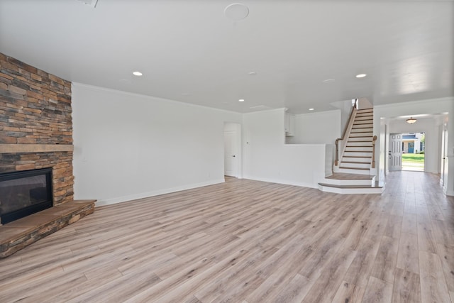 2039 Friendship Dr, Spring Hill, TN 37174 - unfurnished living room featuring crown molding, light wood finished floors, a stone fireplace, stairs, and recessed lighting