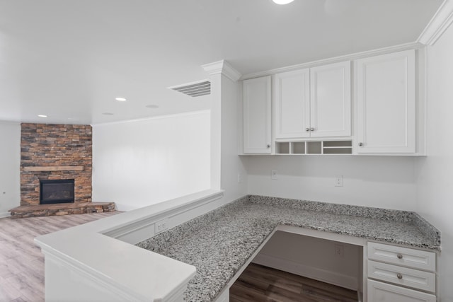 2039 Friendship Dr, Spring Hill, TN 37174 - kitchen featuring a peninsula, white cabinetry, recessed lighting, wood finished floors, and a stone fireplace