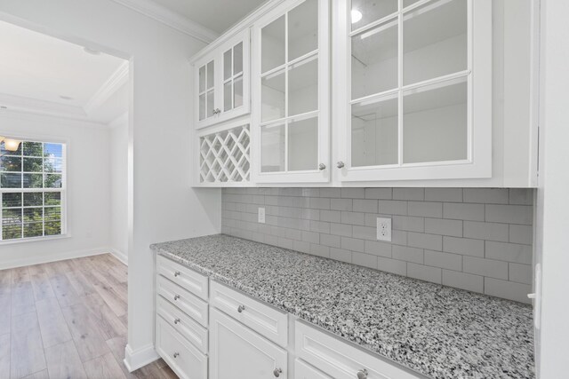 2039 Friendship Dr, Spring Hill, TN 37174 - kitchen featuring crown molding, wood finished floors, light stone countertops, glass insert cabinets, and white cabinetry