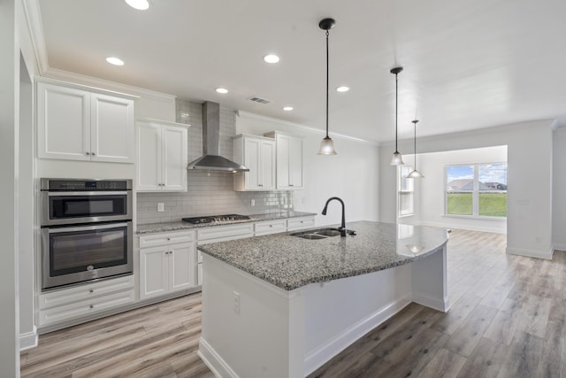 2039 Friendship Dr, Spring Hill, TN 37174 - kitchen with wall chimney exhaust hood, stainless steel appliances, crown molding, white cabinets, and light wood finished floors
