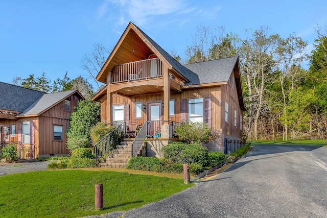 31 Bradley Ln, Bath Springs, TN 38311 - view of front of property featuring a balcony, a front yard, roof with shingles, driveway, and board and batten siding